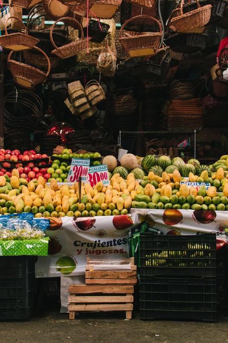Market stall stacked with mangoes and woven baskets