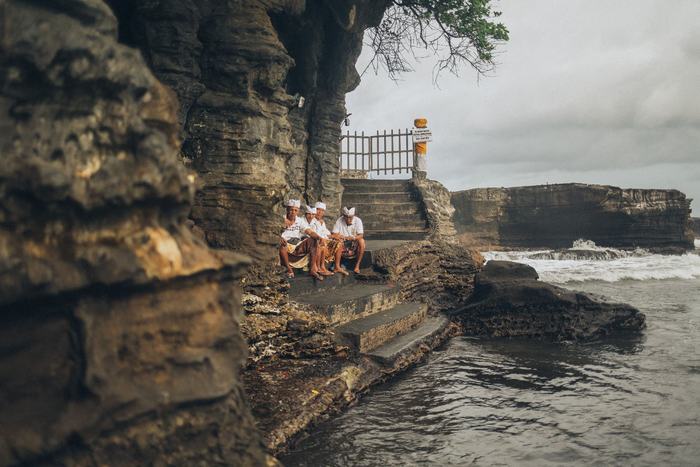 Locals resting by a cliff-side temple entrance