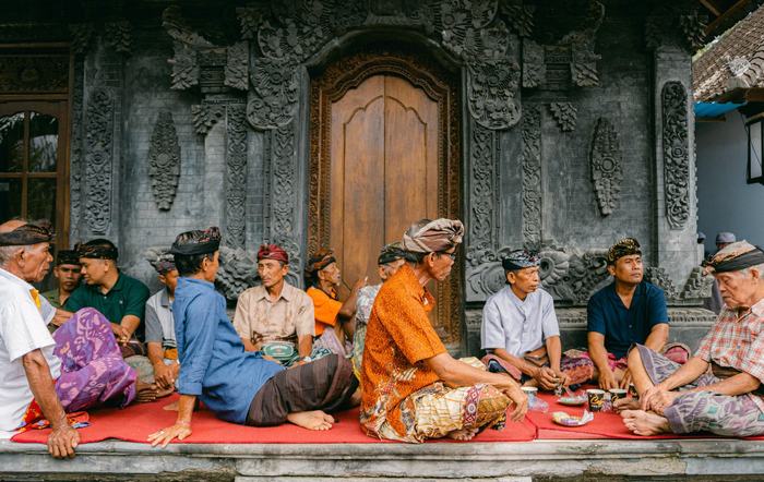 Villagers seated at a carved temple courtyard