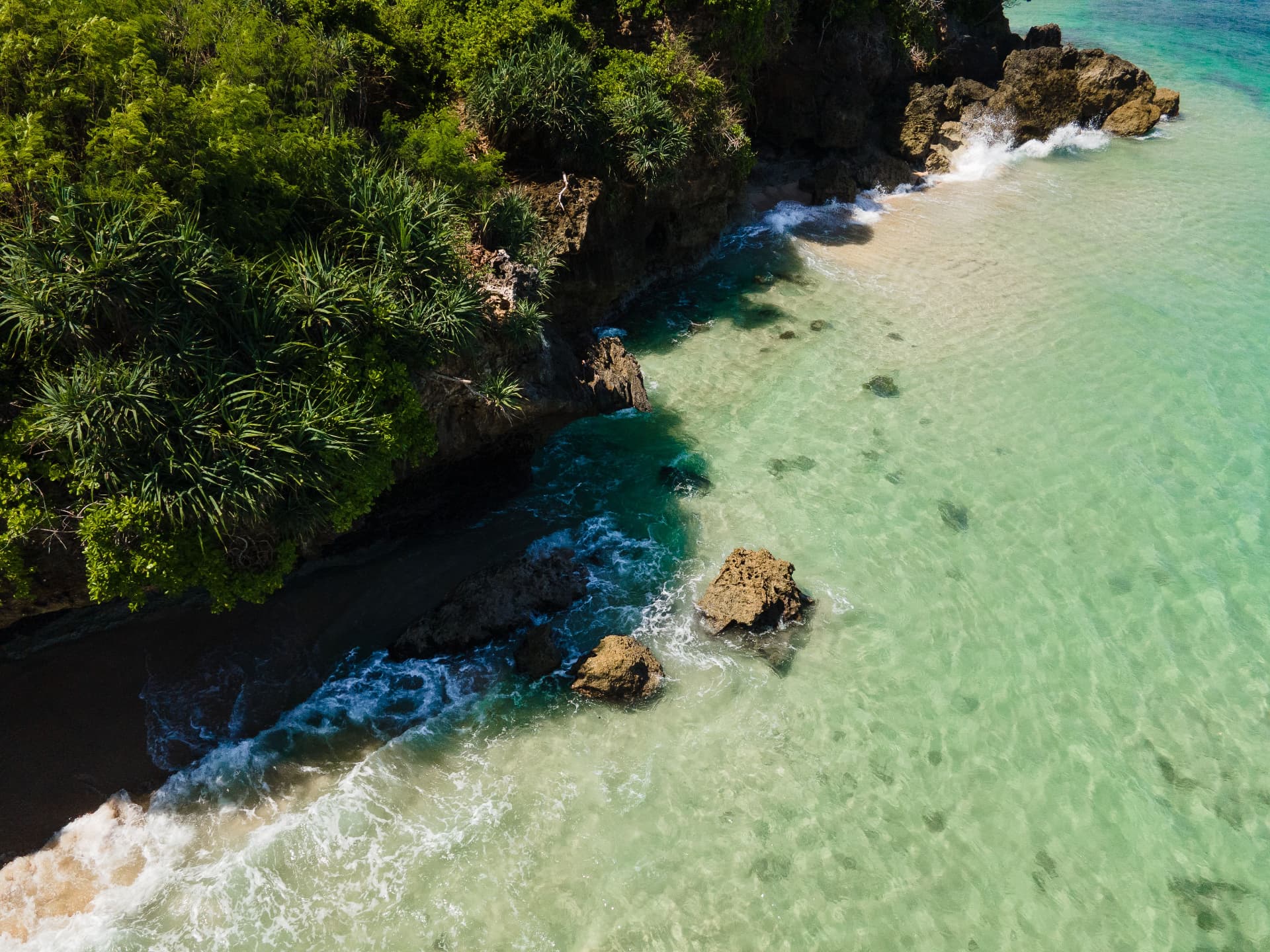 Aerial view of a turquoise cove and rocky headland on the Bali coastline