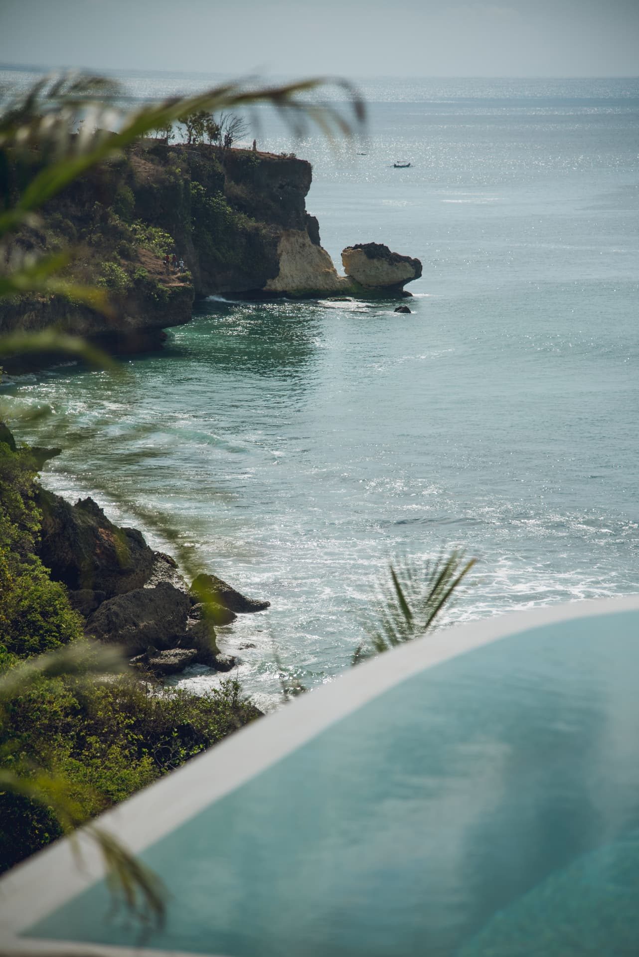 View over an infinity pool towards the Uluwatu cliffs and ocean