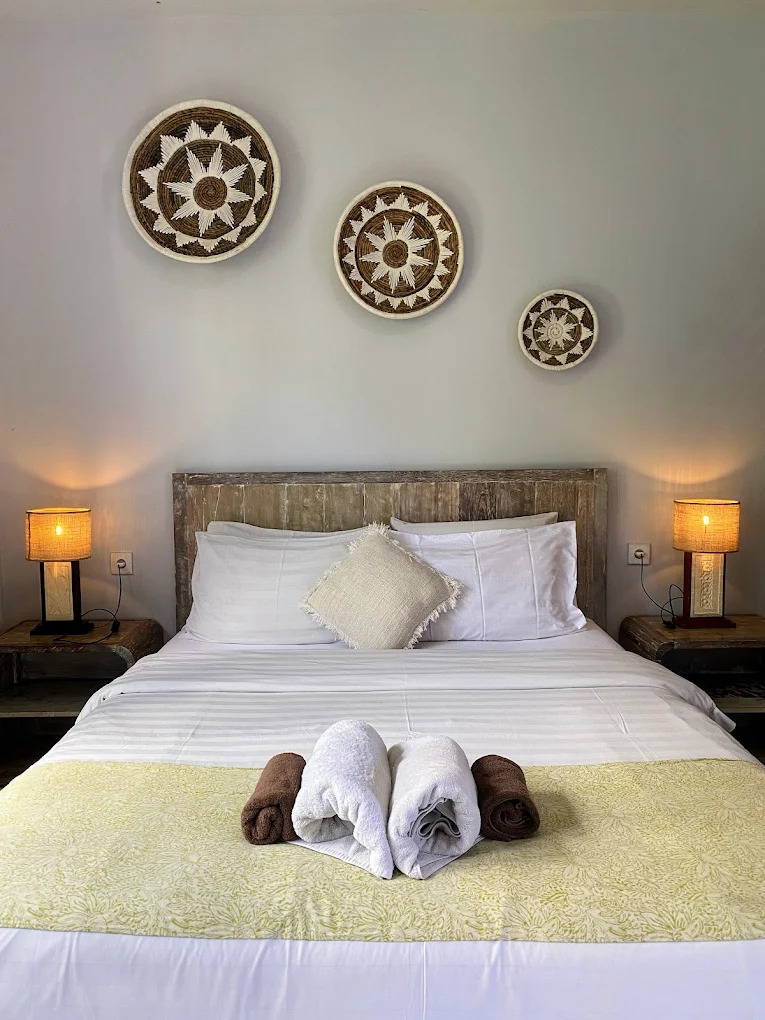 Made bed with white linen, woven wall baskets and warm bedside lamps
