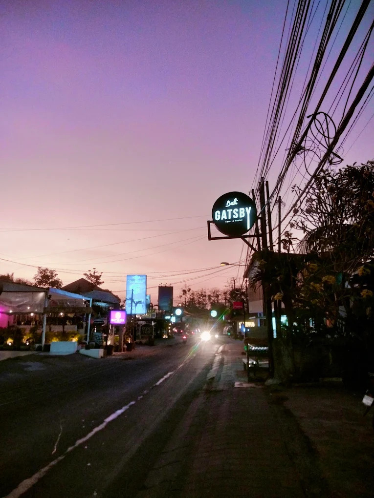 The Gatsby street sign photographed at dusk against a purple and orange sky