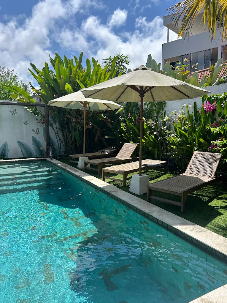 Sun loungers under large umbrellas beside the turquoise pool
