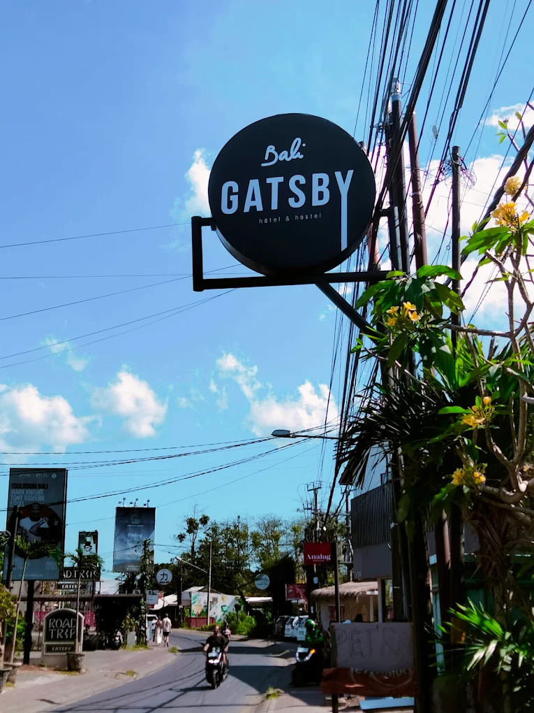 Circular black street sign reading Bali Gatsby hotel and hostel