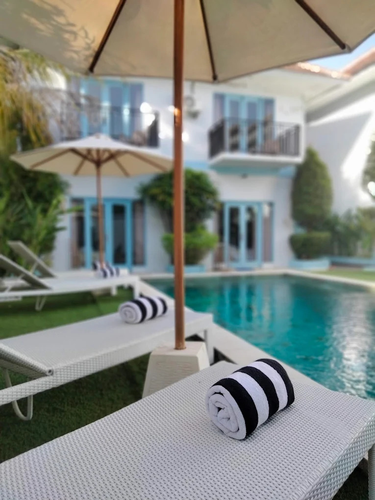 Close up of a rolled striped towel on a white sun lounger
