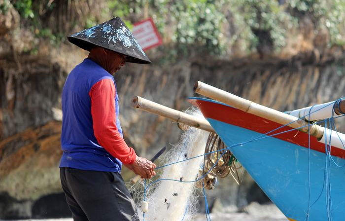 Fisherman working on a blue outrigger boat