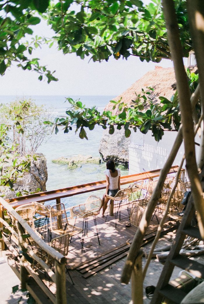 Guests on a rattan furnished timber deck above the ocean