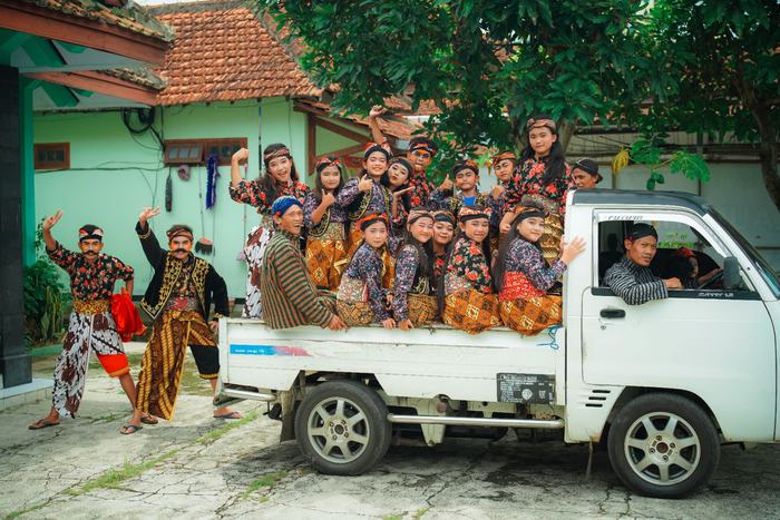 Dance troupe in costume riding a pickup truck